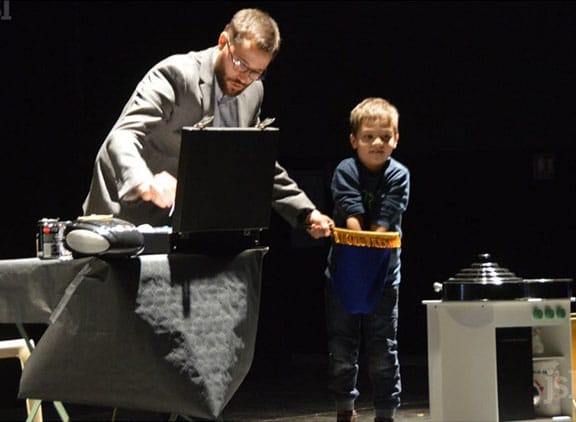 Matt le magicien tient une quêteuse à un enfant qui mélange à l'intérieur à l'occasion d'un spectacle enfant